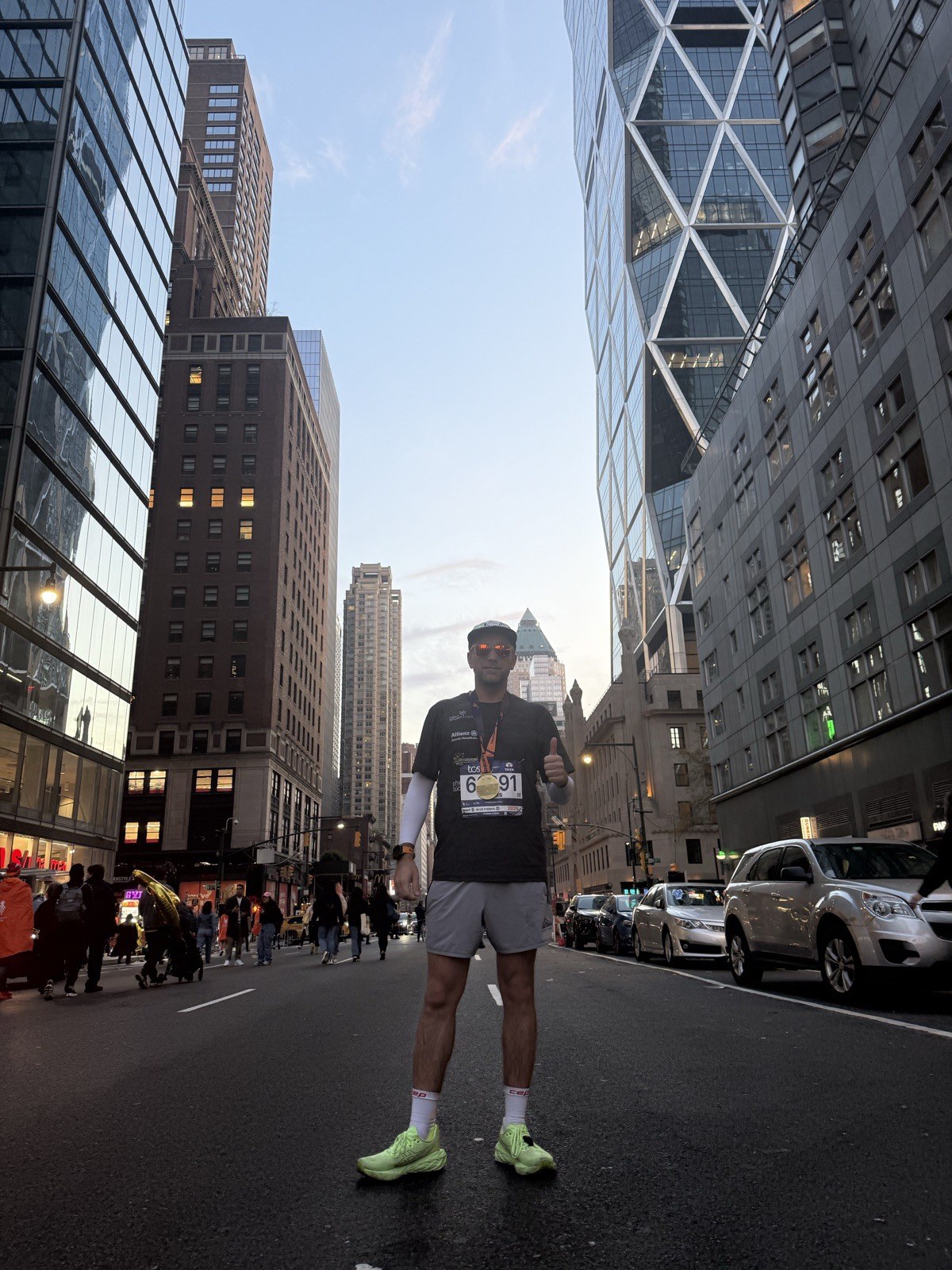 Dennis steht mitten in einer Straße in Manhattan, Startnummer auf der Brust, vor der New Yorker Skyline – New York Marathon 2025.